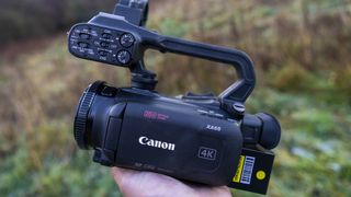 The Canon XA65 camcorder being held in a female hand at sunrise