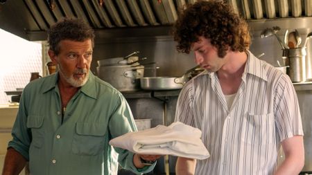 Antonio Banderas handing Dominic Sessa a chef's jacket in Tony.