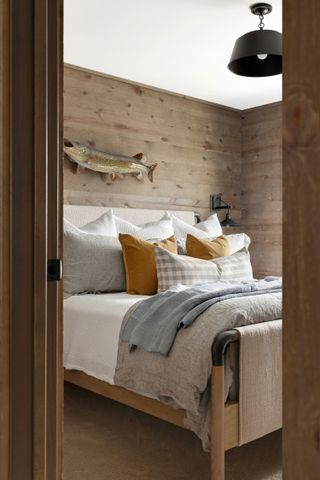 Bedroom doorway with fish on wooden walls neutral bedlinen blue throw and mustard pillows