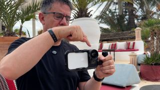 A person pointing to an iPhone in a Neewer Cage