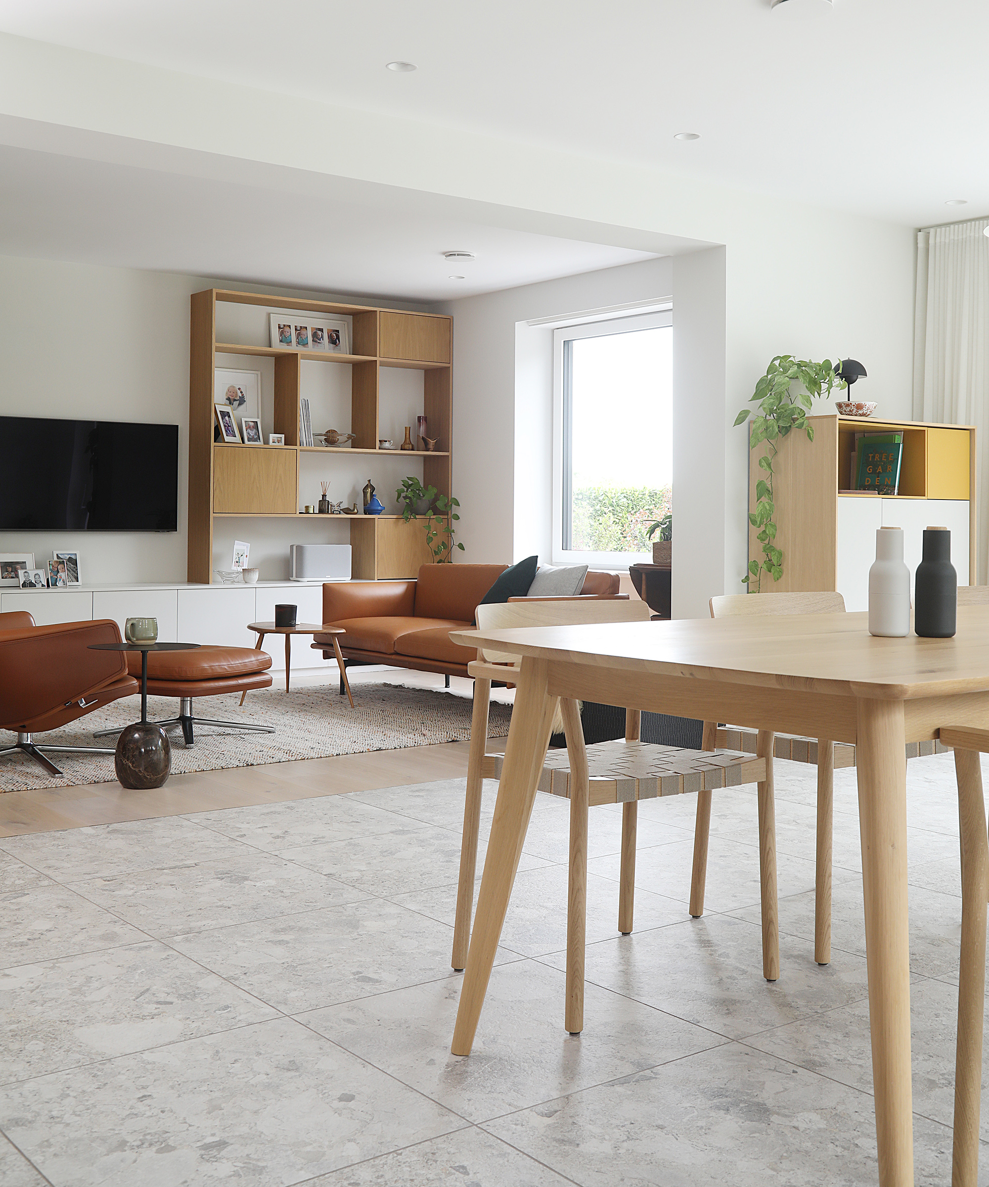 An open plan living and dining room space with mid century furniture and white walls