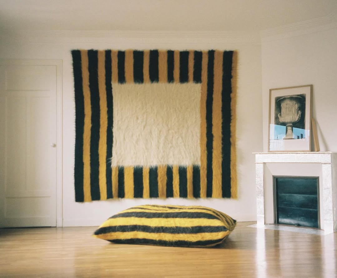 Grace Atkinson yellow and black striped throw hanging on wall, and yellow and black striped cushion on floor