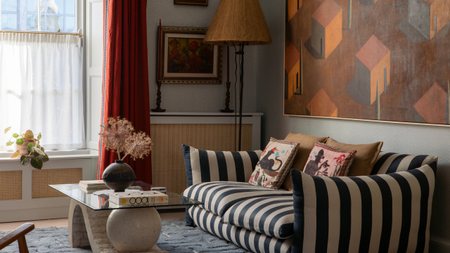 a living room with a striped couch, a large painting on the wall, and an artistic coffee table 