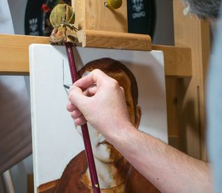 Mahlstick on easel with person painting