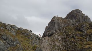 people scrambling on a mountain ridge