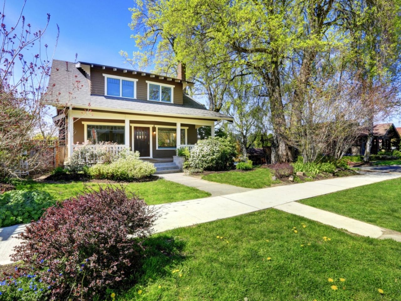 A two story home with a lawn and concrete paths