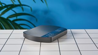 a luxury coffee scale made by Felicita Arc is photographed against a blue background with its weight, USB-C cable, and silicone mat