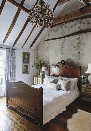 vintage bedroom with beams and floral feature wallpaper by Flora Roberts at Hamilton Weston