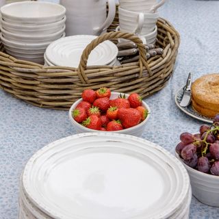 Outdoor dining table with plates, bowls of fruit and cake