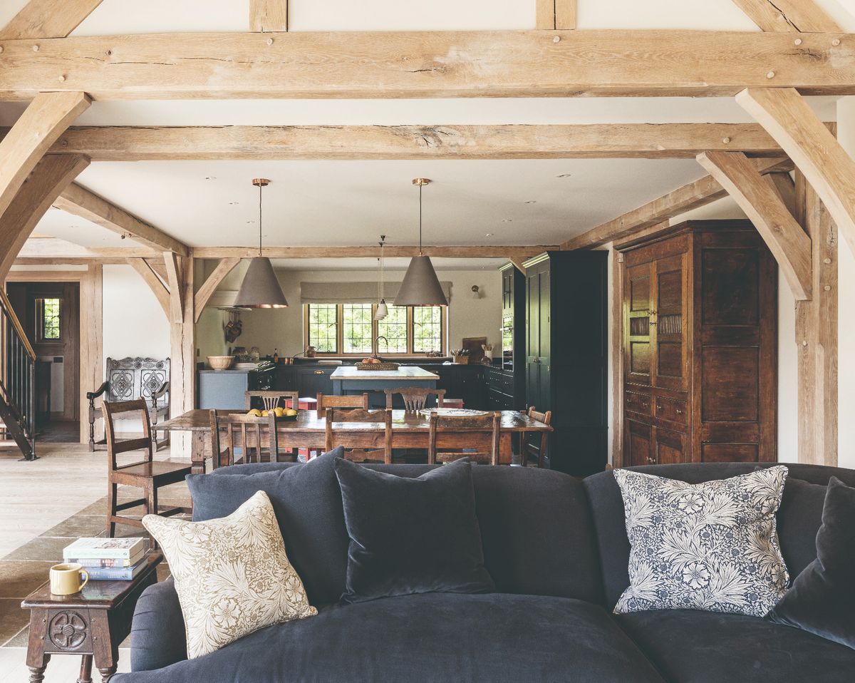 An open plan modern rustic home interior with a velvet sofa, dining table and kitchen
