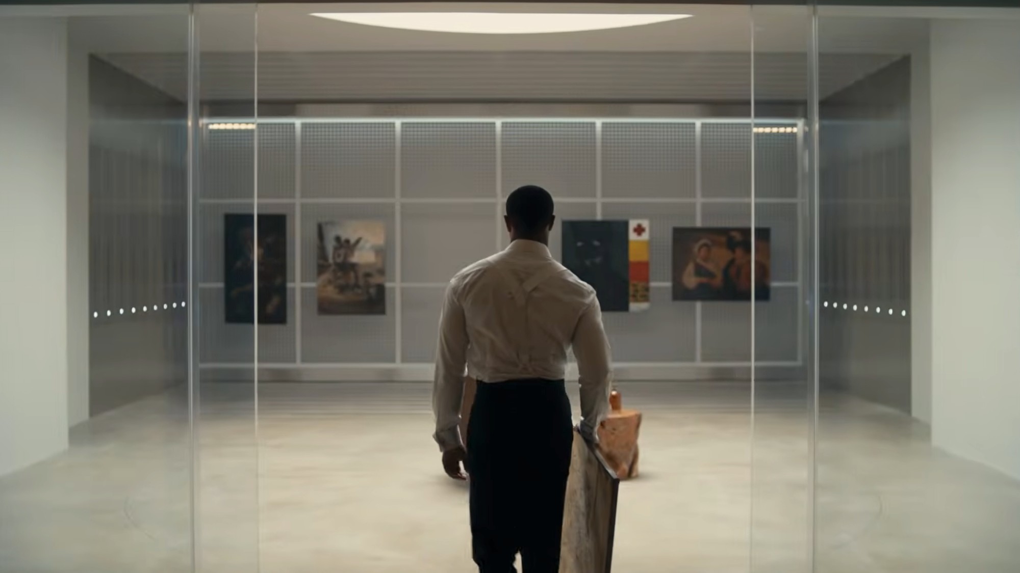 Michael B. Jordan with his back to the camera walking though glass doors into an art gallery