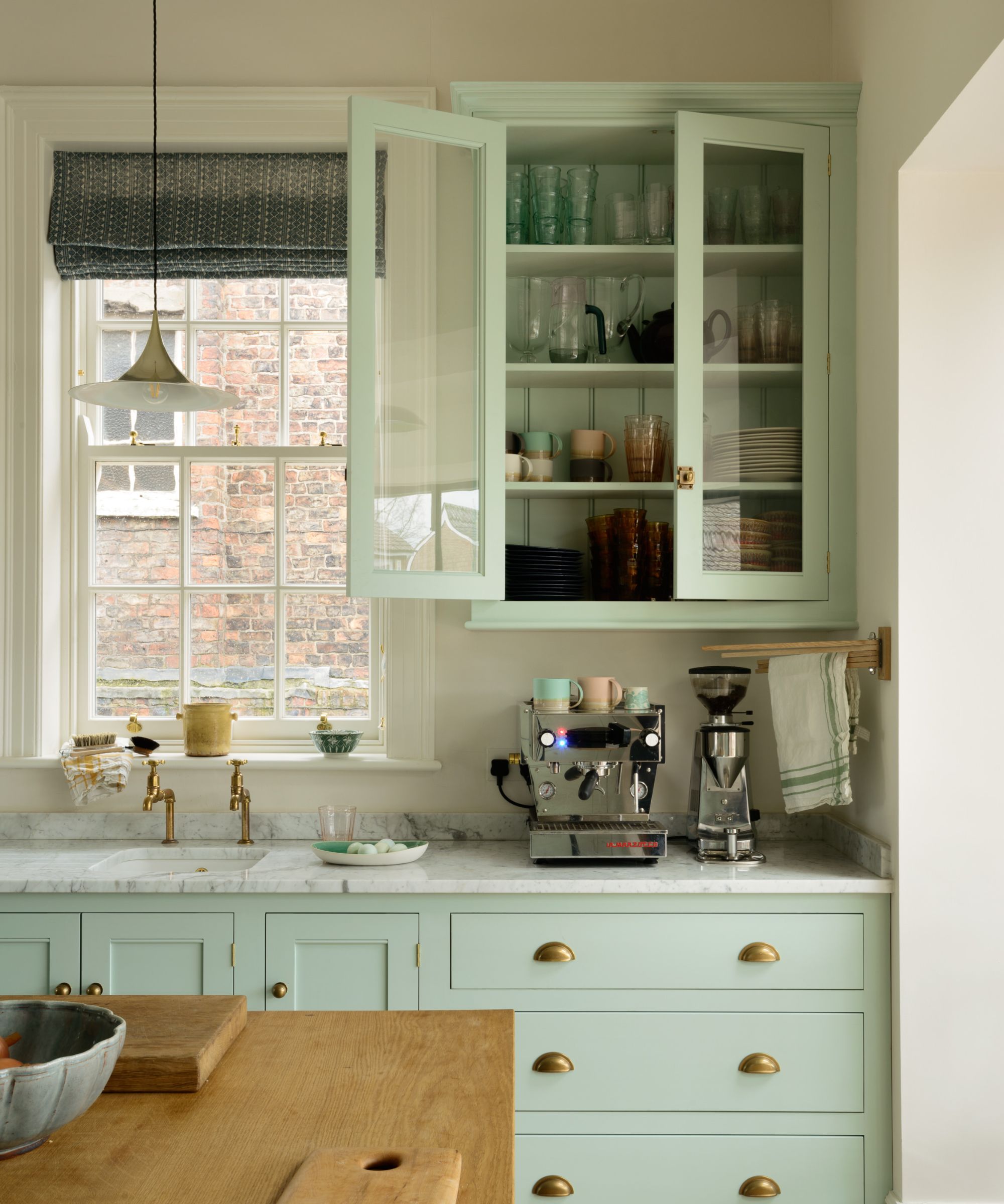 A light blue kitchen with wooden countertops and paneling at the back of the wall cupboards
