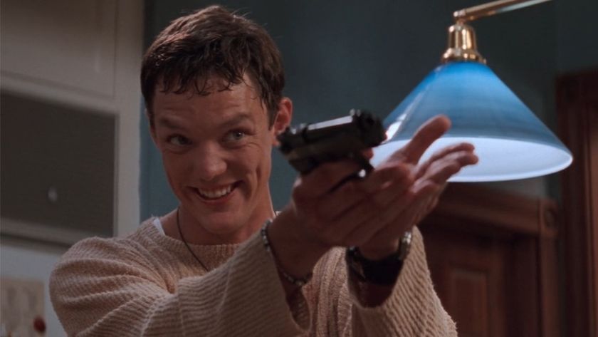 Stu holding a gun and smiling in Scream. 