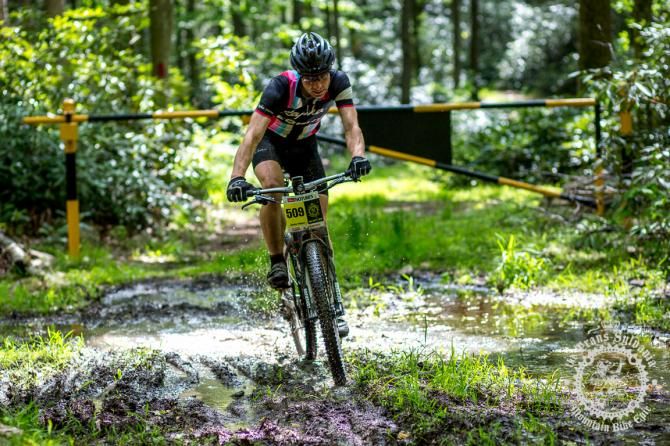 Jeremy Powers rides under a gate and through the mud of Stage 6