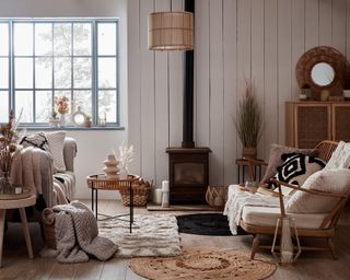 A cozy Scandinavian brown and grey living room with rattan light fixture, jute rug and layered throws
