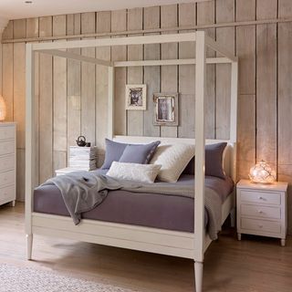bedroom with four poster bed wooden flooring and wood panel wall