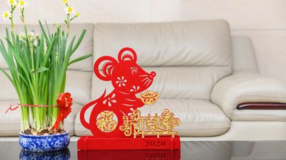 A pot of daffodils next to a Lunar New Year rat sculpture