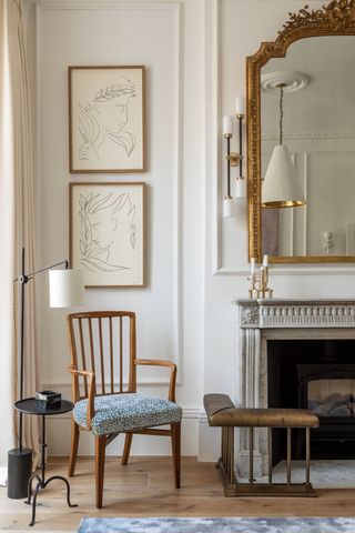 A fireplace with a stone mantel, a gilt mirror, and a brass club fender