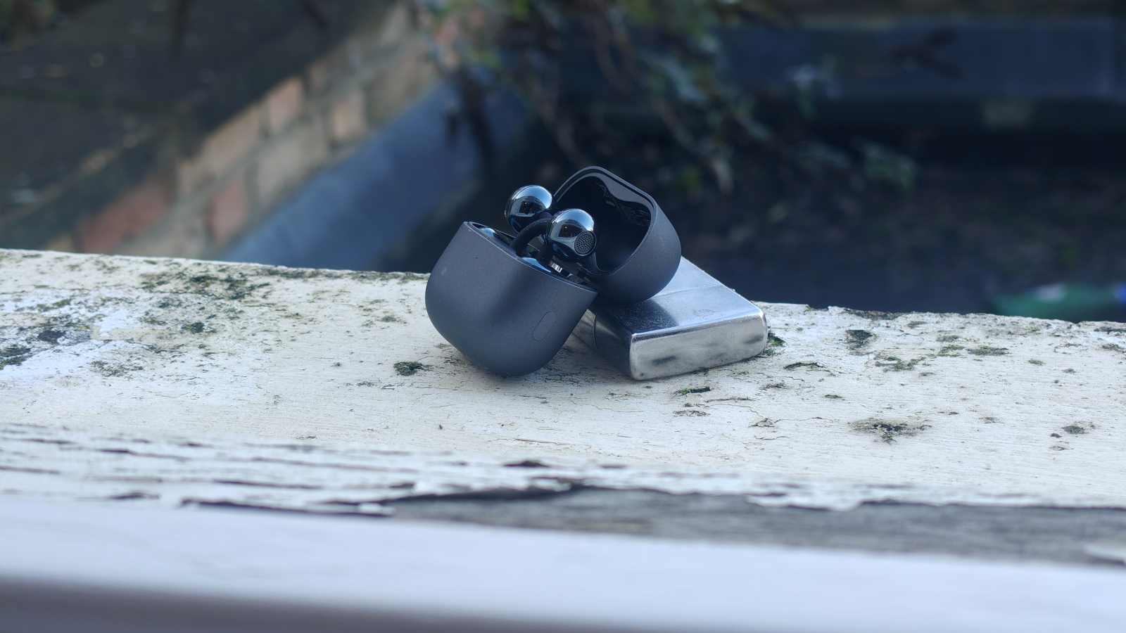 The Huawei FreeClip 2 buds in a case, leaning on a zippo lighter.