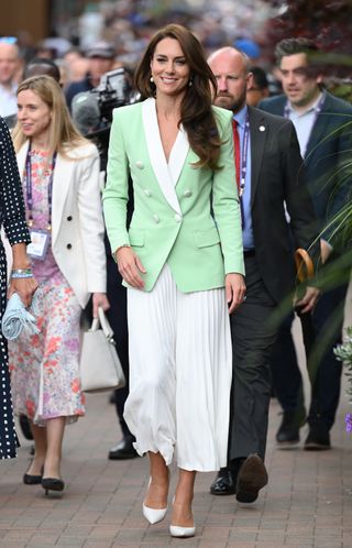 Kate Middleton attends Wimbledon 2023 wearing a mint green blazer, white pleated skirt, and white pumps