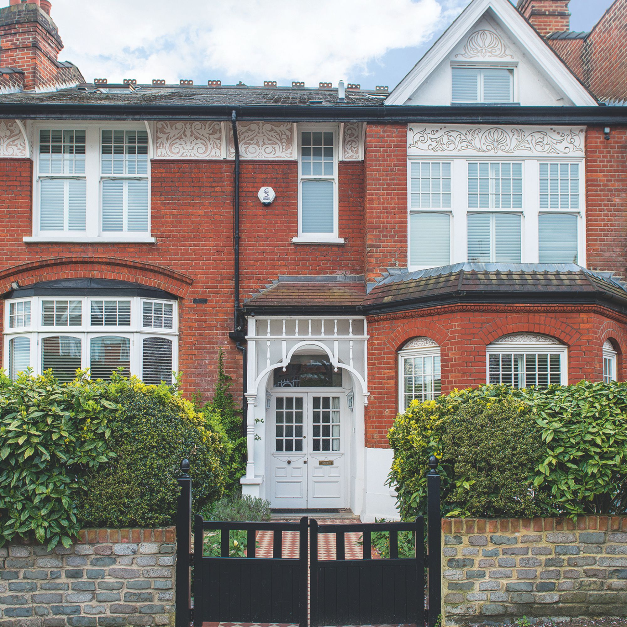 Front of a period property with a tiled pathway leading to a black gate