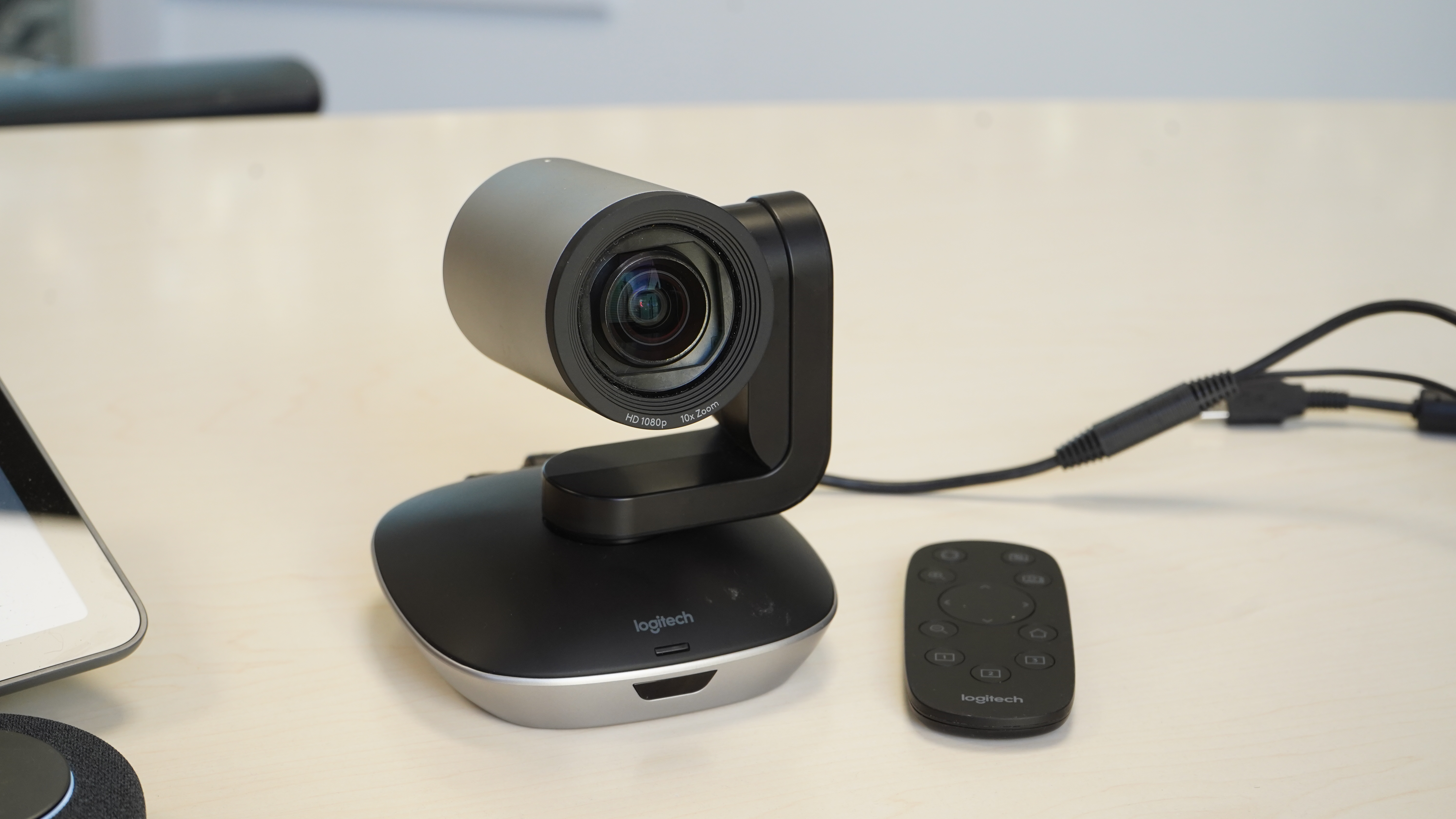Logitech PTZ Pro 2 on a table in meeting room with cables and remote