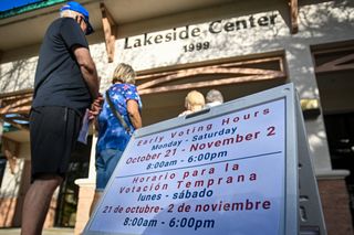 People wait in line to cast their ballots in the first round of early voting at a polling place, October 21, 2024, in Daytona Beach, Florida.