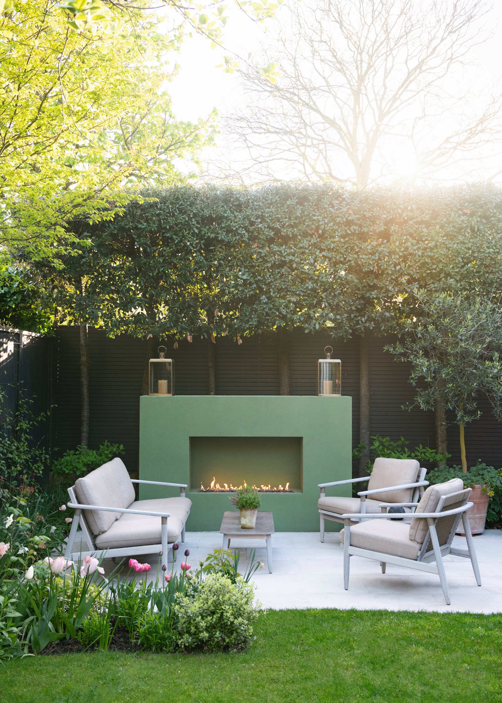 a patio in a modern garden with a green fireplace and outdoor seating