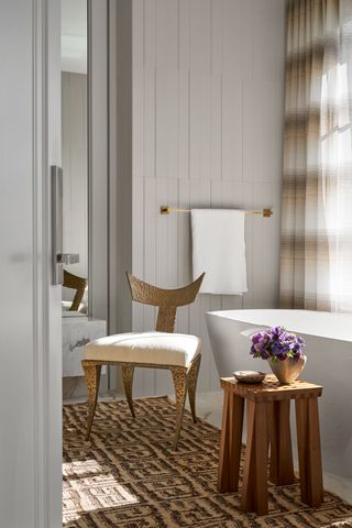 bathroom with contemporary freestanding bath and wooden midcentury chair with painted tongue and groove paneled walls