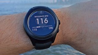 New Balance RunIQ wear OS smartwatch worn on a wrist outdoors.