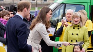 Prince William looks on as Kate Middleton tosses a pancake during a visit to City Hall on March 8, 2011 in Belfast, Northern Ireland.