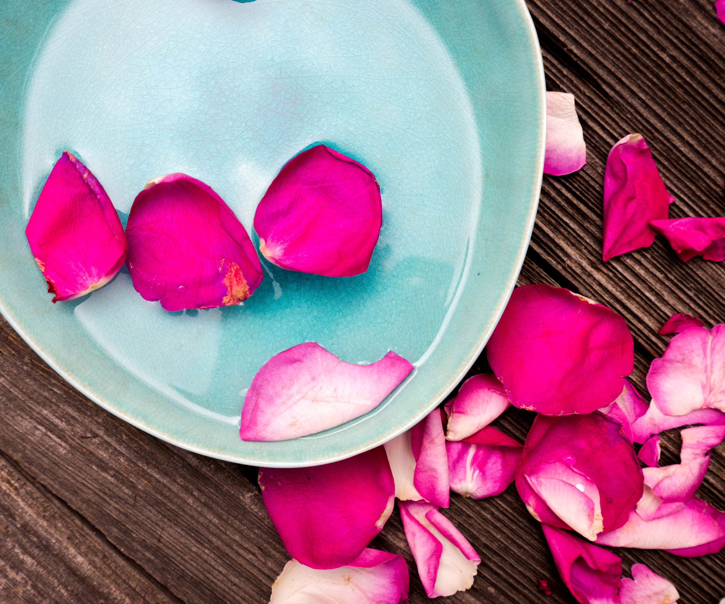 pink rose petals in pale blue bowl on wooden table