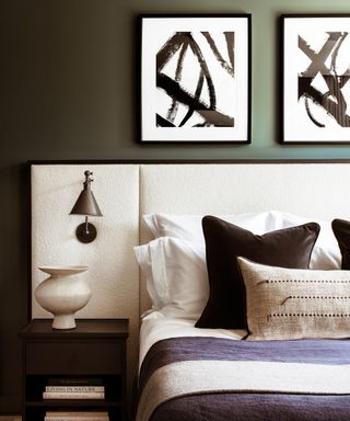 A green-blue bedroom with white boucle-covered headboard and black and white bedding and artwork