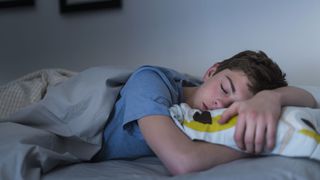 A young boy sleeps on a mattress with a pillow
