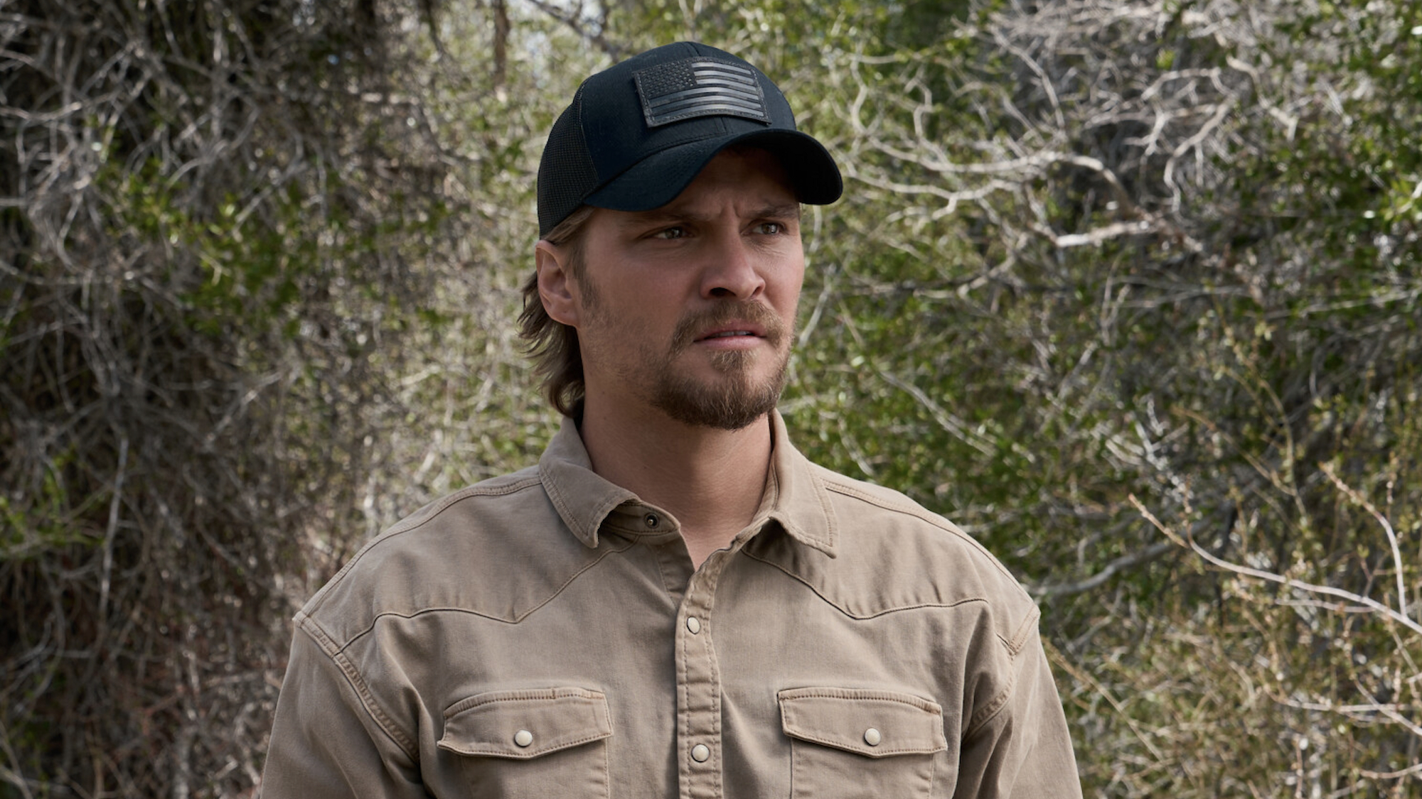 Kayce in black cap and light brown shirt standing outside in Marshals Season 2 premiere