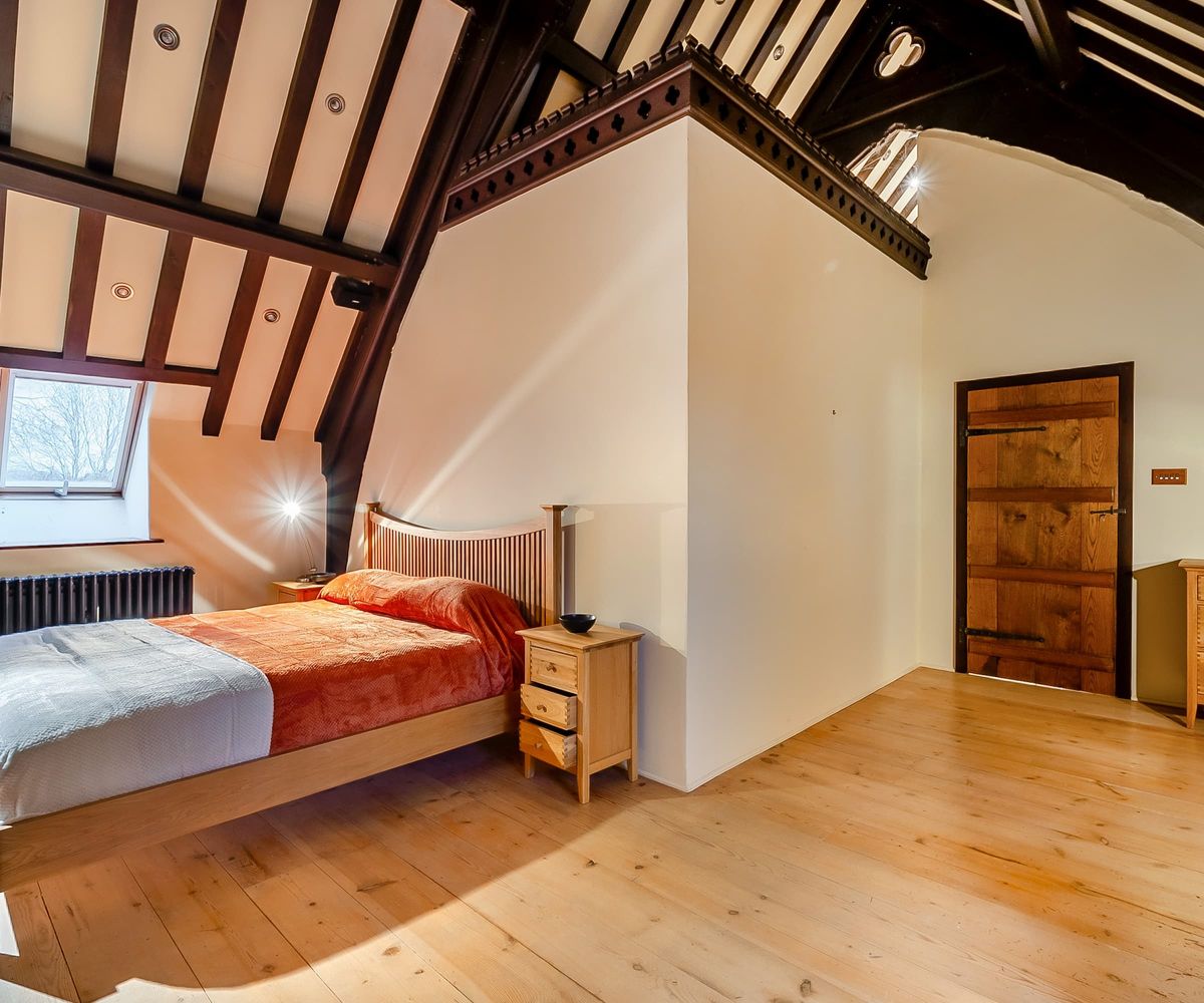 A bedroom with a vaulted ceiling and wooden flooring
