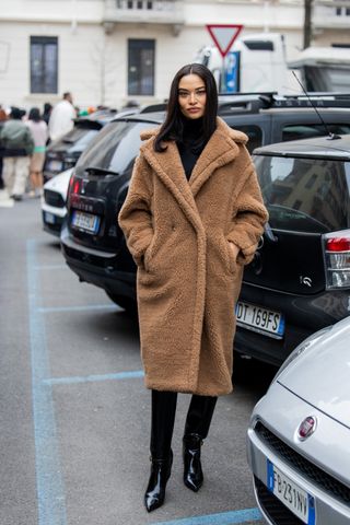 woman wearing long teddy coat, black turtleneck, black pants, and black boots