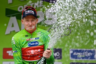Tao Geoghegan Hart celebrates wearing the green leader's jersey at the Tour of the Alps