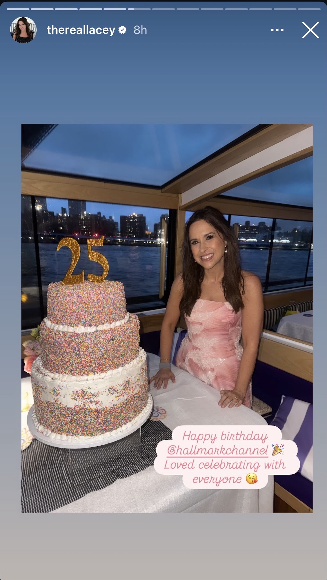 Lacey Chabert posing next to Hallmark's 25th birthday cake for the network's birthday party at sea in an Instagram story.