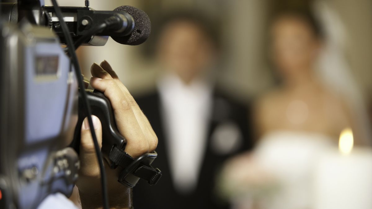 A person holds a video camera to record a bride and groom