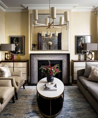 Small living room lighting featuring a statement pendant light reflected in a mantelpiece mirror with a gold color scheme.