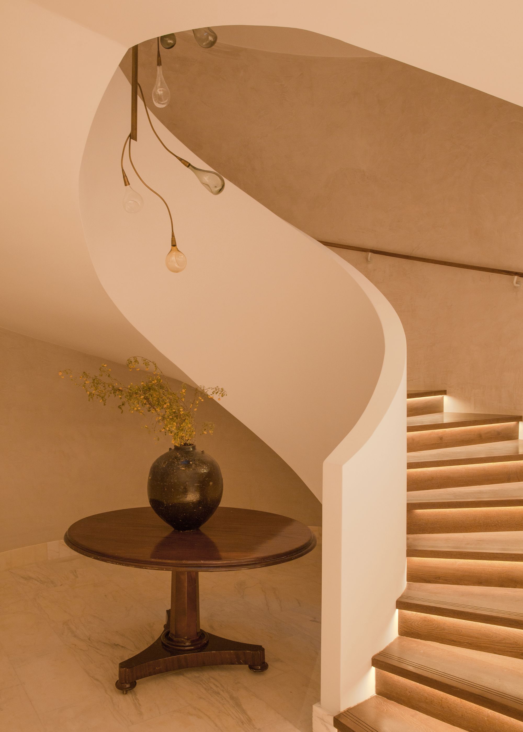 The lower ground floor of the wellness spa features a well-lit staircase and a table adjacent to it, adorned with a vase on top. 