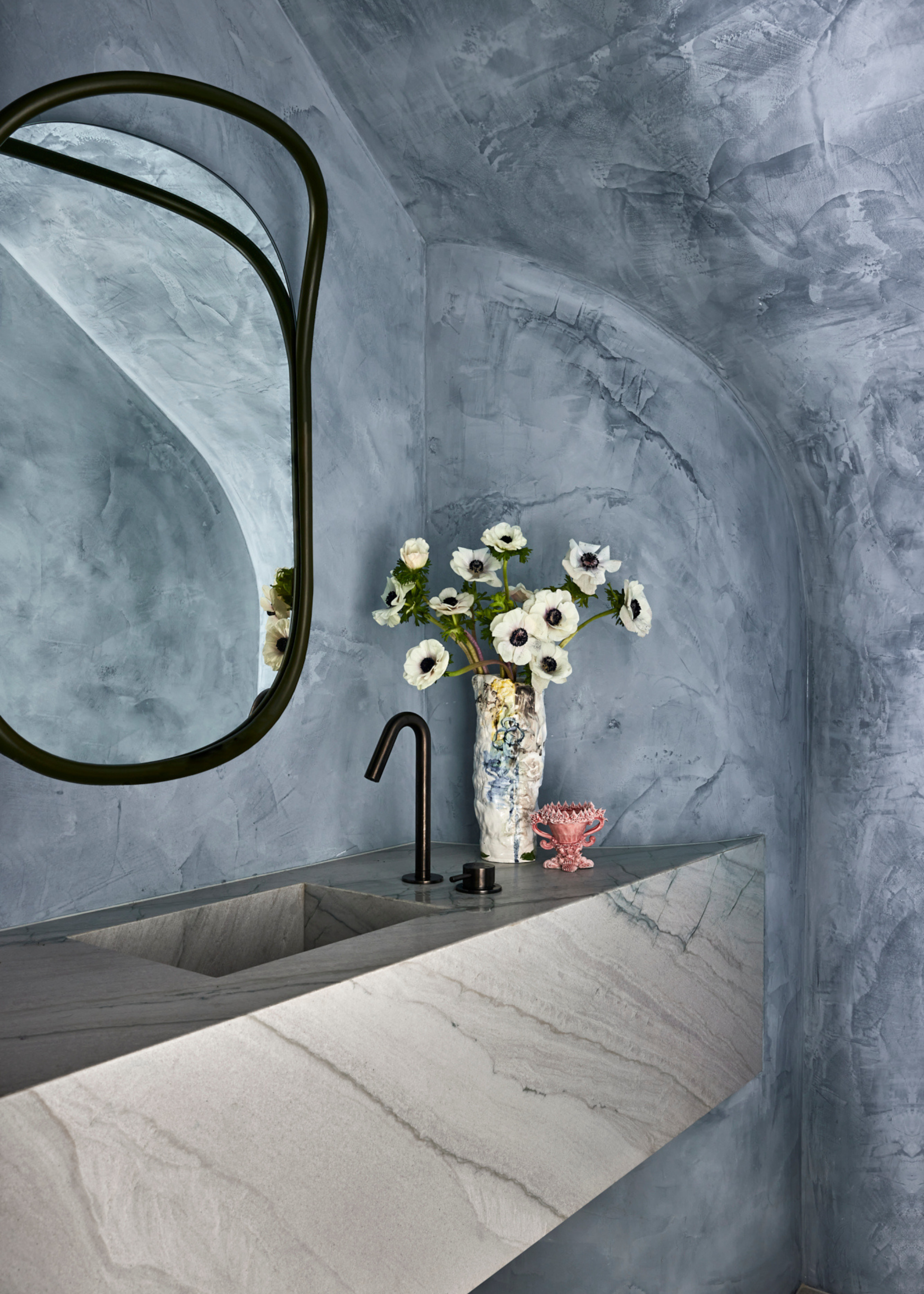 plaster washed walls and grey countertops in small cavernous bathroom