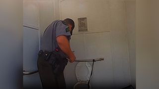 A policeman peering into the toilet to find a trapped woman