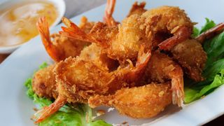 Coconut shrimp on a plate with salad next to sauce