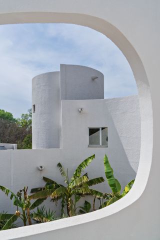 The white modernist architecture of Villa Benkemoun framed by palm trees and blue sky