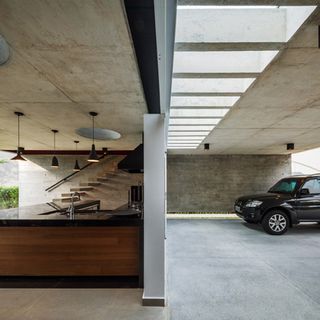 A spacious concrete garage adjacent to the barbecue area becomes an architectural highlight in itself, naturally illuminated by a set of skylights installed in the roof terrace above