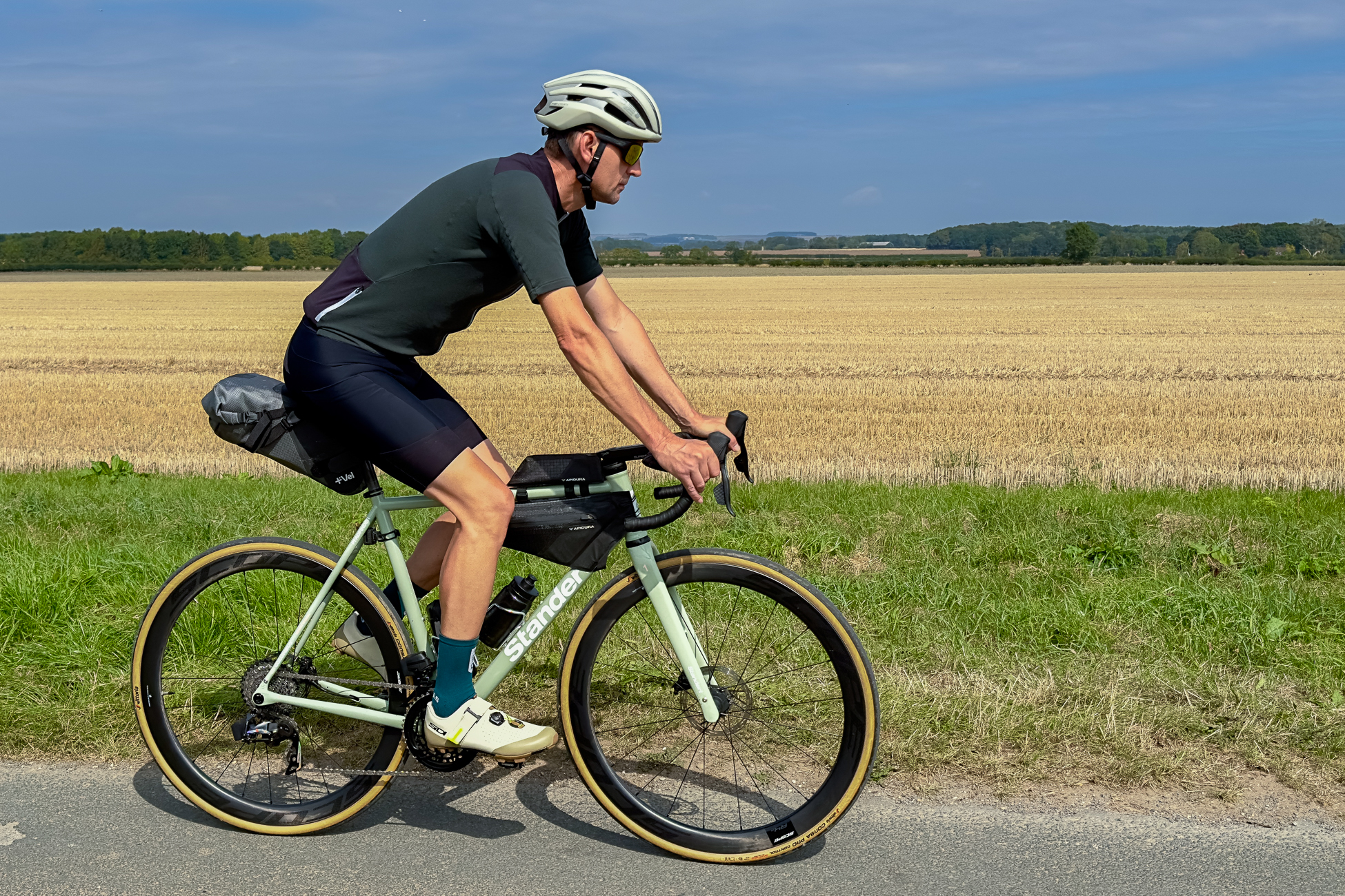 man riding a green bike wearing black shorts, green top, green socks and beige SPD shoes