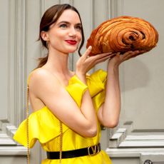 Model holding a comically large croissant in Vestiaire Collective clothing