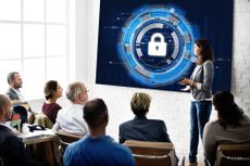 Business classroom with a woman talking about cyber security, blue padlock image on whiteboard